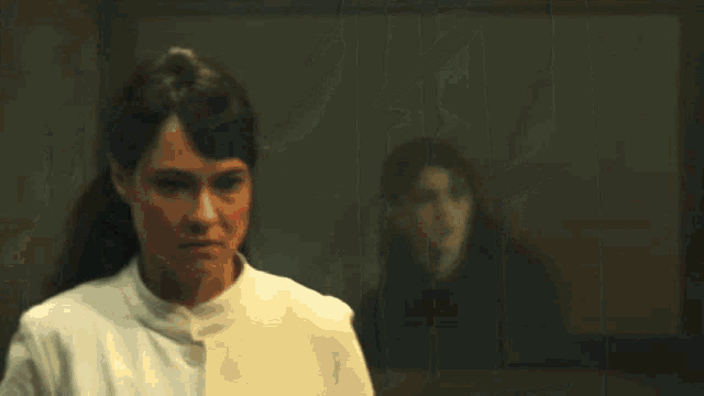 a woman in a white dress stands in a dark room