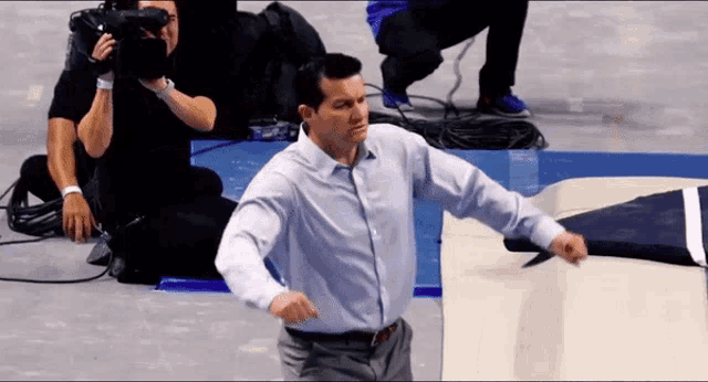 a man in a white shirt is dancing in front of a cameraman
