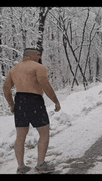 a shirtless man in shorts is standing on a snowy road