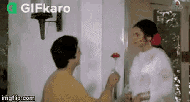 a man is giving a flower to a woman .