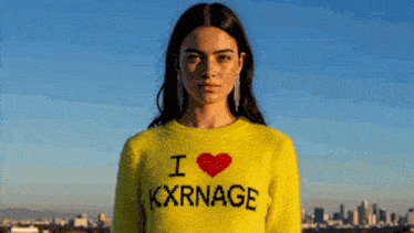 a woman is wearing a yellow sweater that says i love kxrnage