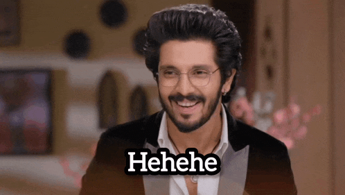 a man with glasses and a beard is smiling with the word henehe written below him