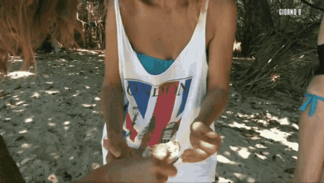 a woman wearing a london tank top holds something in her hand