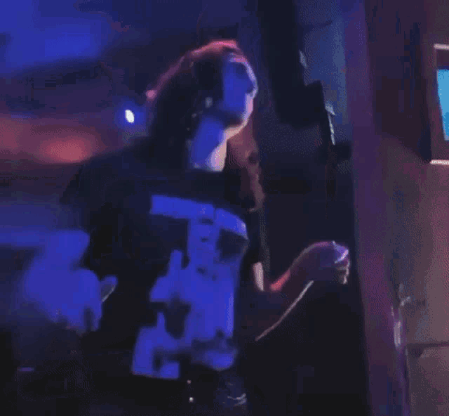a woman is dancing in a dark room with a blue light behind her