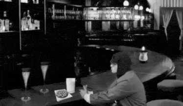 a man sits at a bar with a pizza on a napkin