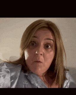 a woman in a blue shirt is making a funny face