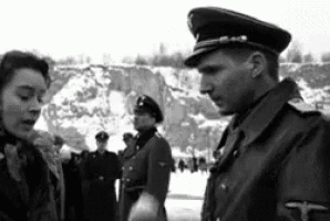 a black and white photo of a man in a military uniform standing next to a woman .