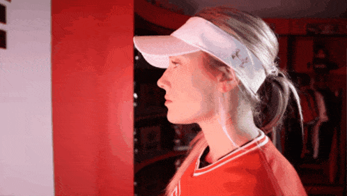 a woman wearing a white visor and a red shirt with the letter a on it