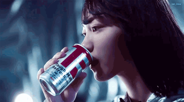 a woman drinking from a can that says ' rough ' on it