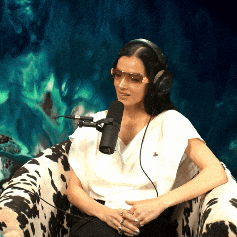 a woman wearing headphones and sunglasses is sitting in front of a microphone in a cow print chair