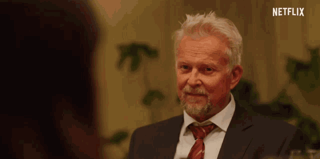 a man in a suit and tie is talking to a woman with a netflix logo in the background