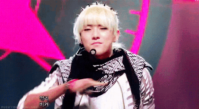 a man with blonde hair is wearing a scarf around his neck and a microphone in his hand