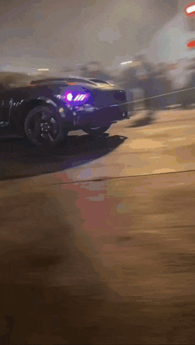 a purple car with a purple headlight is driving down the road