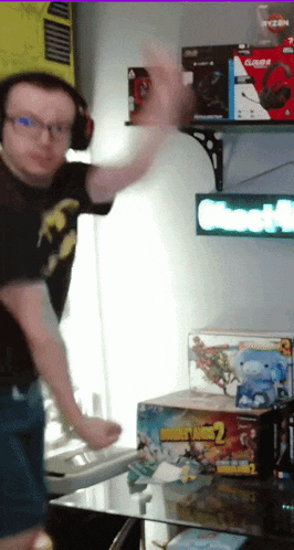 a man wearing headphones stands in front of a shelf with a box of borderlands 2 on it