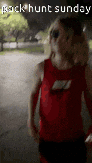 a person in a red nike tank top is walking down the street at night .