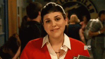 a woman in a red sweater is smiling in front of a mtv sign .