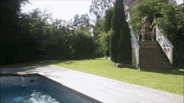 a woman in a bathing suit stands on a set of stairs next to a pool