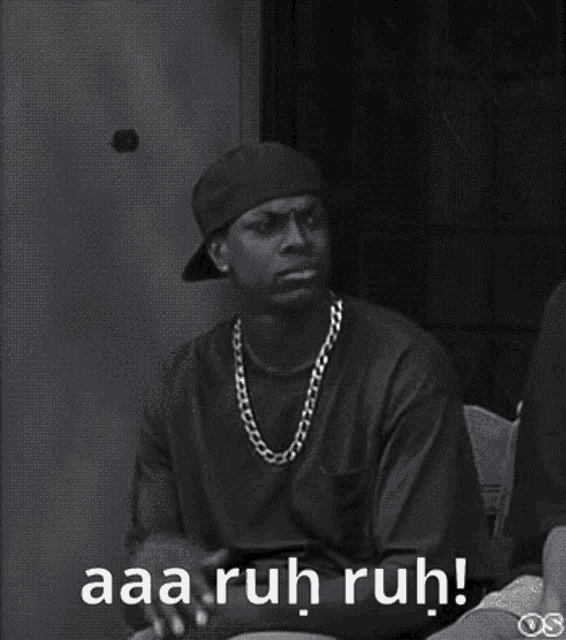 a black and white photo of a man sitting in a chair with the words `` aaa ruh ruh '' written on the bottom .