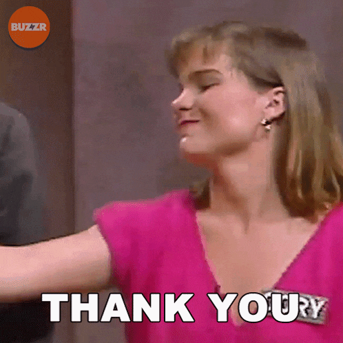 a woman in a pink shirt is giving a thank you sign
