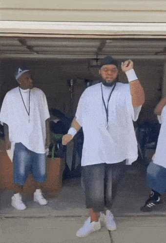 a group of men are dancing in a garage with one wearing a hat with the letter a on it