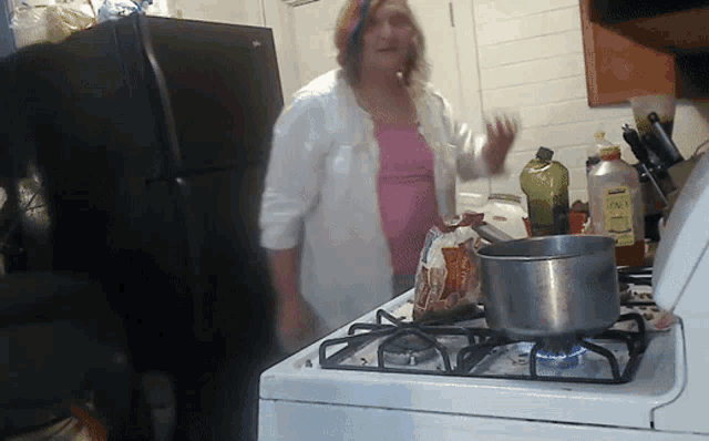 a woman is cooking on a stove with a bottle of olive oil on it