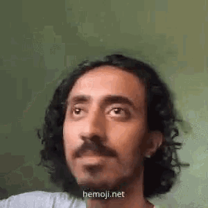 a man with curly hair and a mustache is making a face .