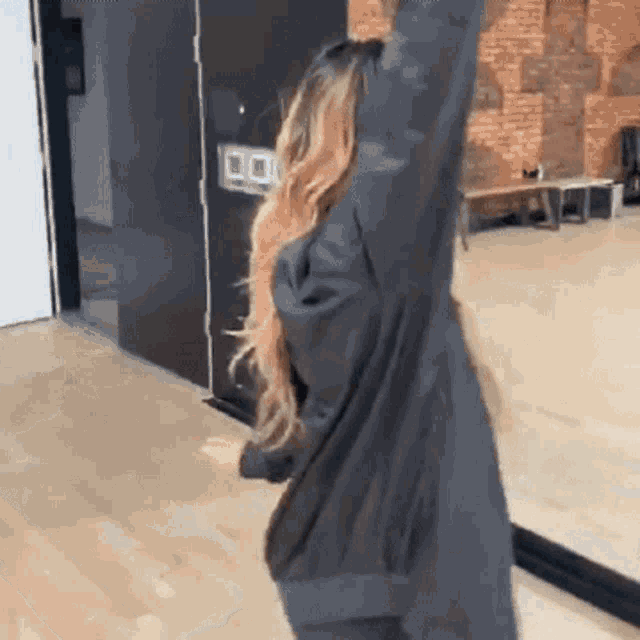 a woman in a black coat is dancing in front of a mirror