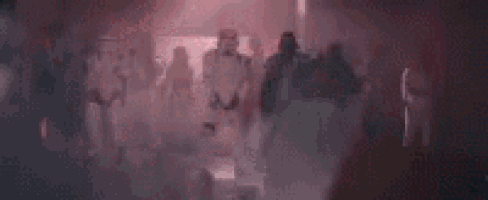 a blurred image of a group of people standing in a dark room .
