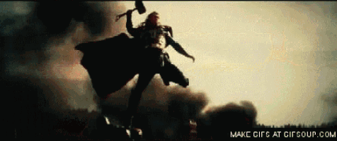 a man in a cape is flying through the air with a hammer in his hand .