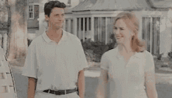 a man in a white shirt is standing in front of a house .