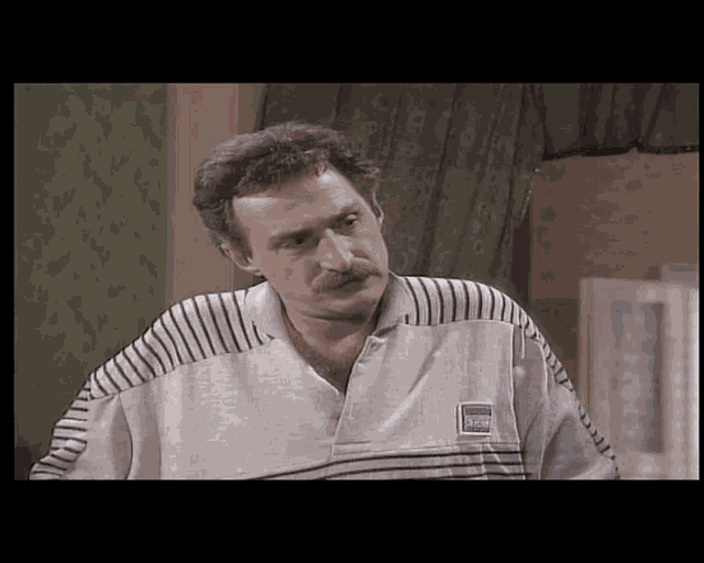 a man with a mustache is wearing a striped shirt that says ' reebok ' on it