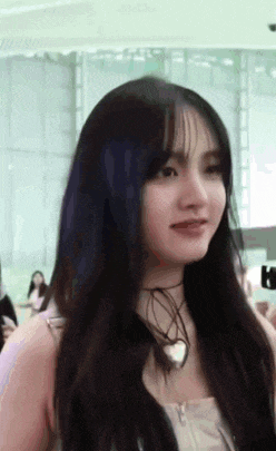 a close up of a woman 's face with long hair and a choker around her neck .