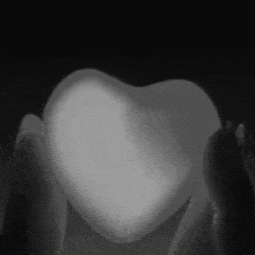 a black and white photo of a person holding a heart shaped object .