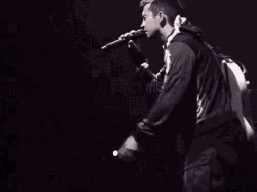 a man is singing into a microphone with a skull on his shirt