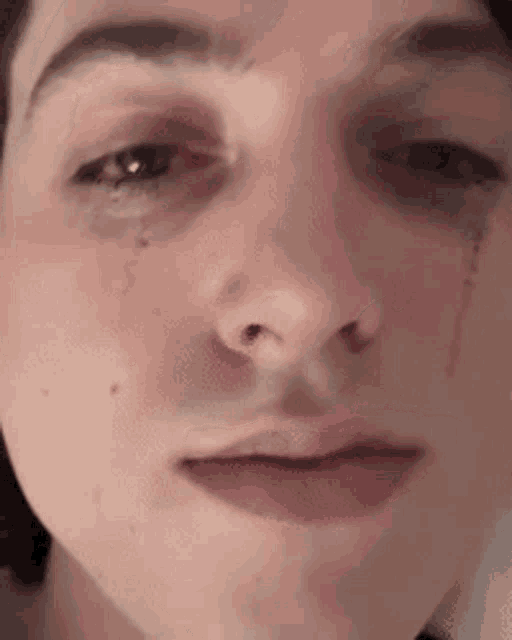 a close up of a person 's face with a tear coming out of their eye .