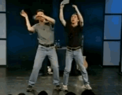 two men are dancing on a stage with their arms up in the air