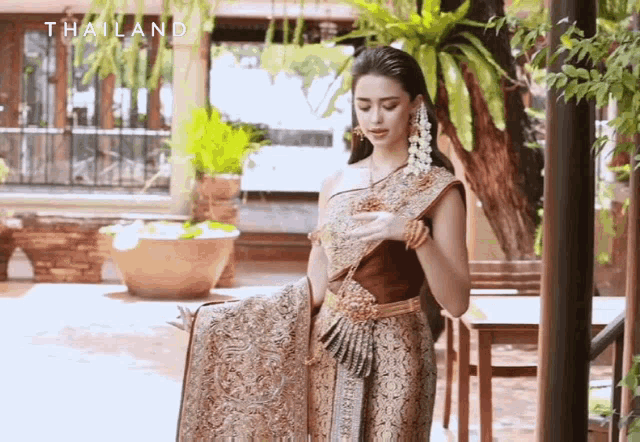 a woman in a traditional costume from thailand is standing in a garden