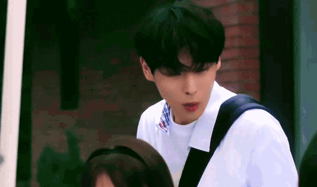 a young man with a backpack is standing next to a young girl and looking at her .