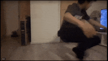 a man is squatting down in front of a computer screen that says ' cinema '