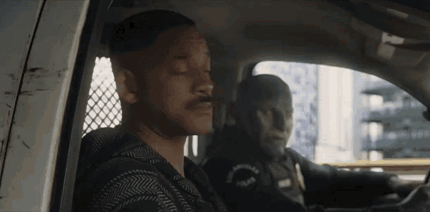 a man with a mustache is sitting in the back of a police car .