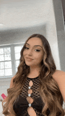 a woman with long hair is taking a picture of herself in front of a window