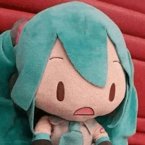 a stuffed toy of hatsune miku is sitting on a red couch with a surprised look on her face .