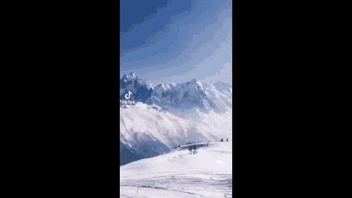a snowy mountain with a blue sky and a tiktok logo on the bottom
