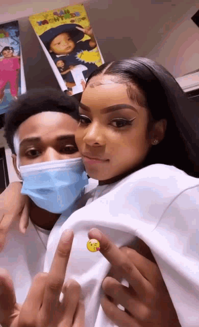 a man and a woman wearing face masks are standing next to each other and giving the middle finger .