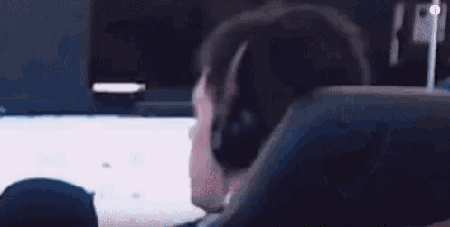 a man wearing headphones is asking what while sitting in front of a computer screen .