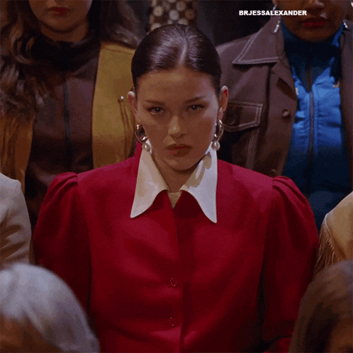 a woman in a red jacket and white collar is surrounded by other women with the caption brjessalexander