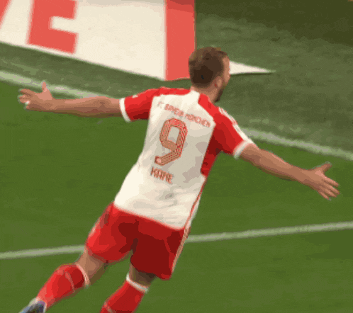 a soccer player with the number 9 on his back jumps in the air
