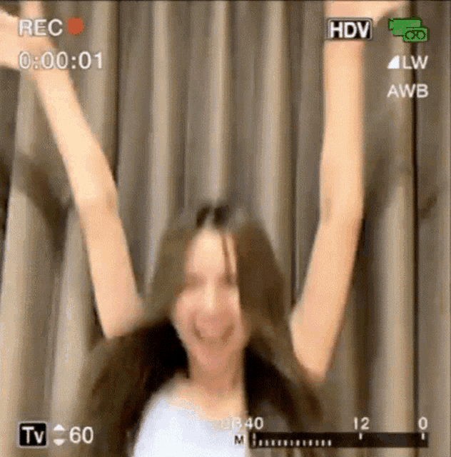 a woman is dancing with her arms in the air in a video .