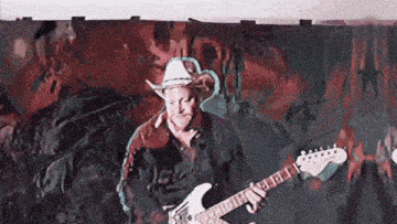 a man wearing a cowboy hat is playing an electric guitar