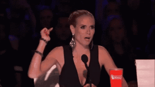 a woman in a black dress is sitting in front of a microphone with a red cup in front of her .
